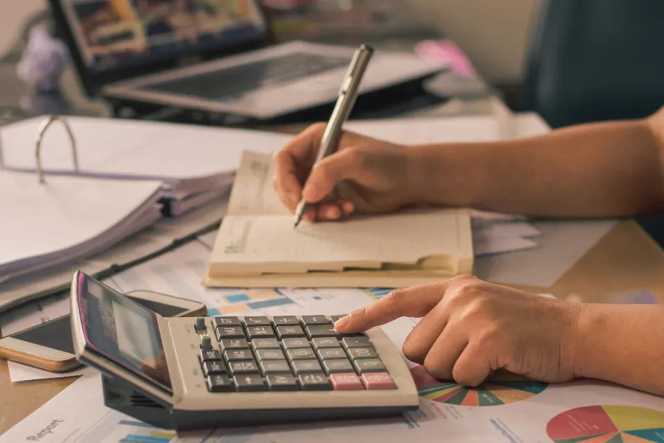 Calculator, notebook and financial charts on a desk during bookkeeping work